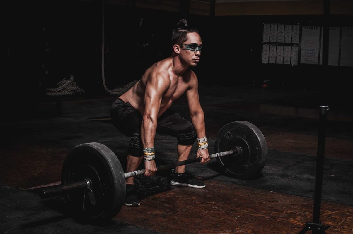 shirtless man lifting barbell